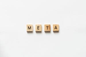 META spelled out with wooden letter tiles on white surface.